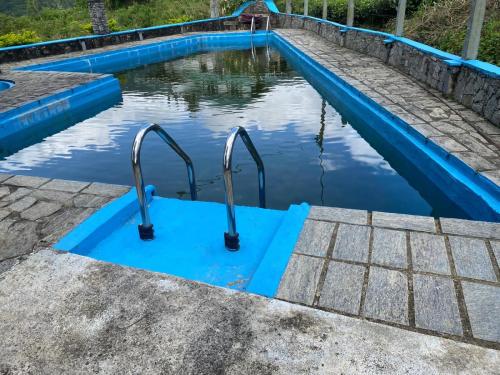 a swimming pool with a blue coping and stairs in the water at Misty mountains residents in Huluganga