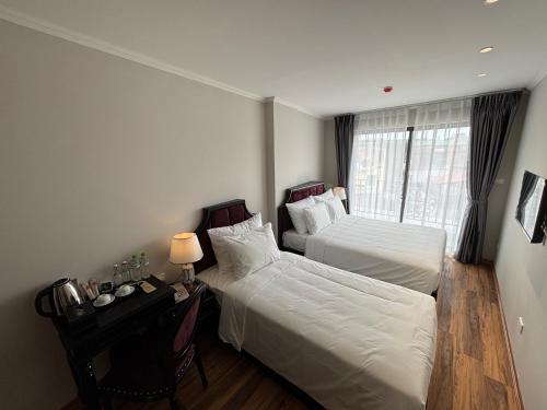 a hotel room with two beds and a desk and a window at Classy Central Hotel in Hanoi