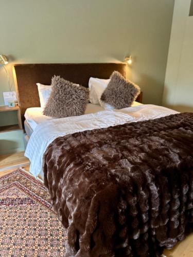 a bed with a brown blanket and pillows on it at Lomma Station Inn in Lomma