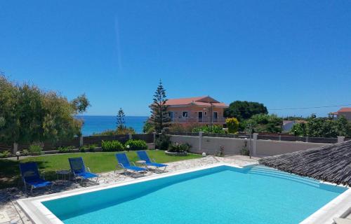a swimming pool with chairs and a house at Skidi Beach house in Ágios Matthaíos