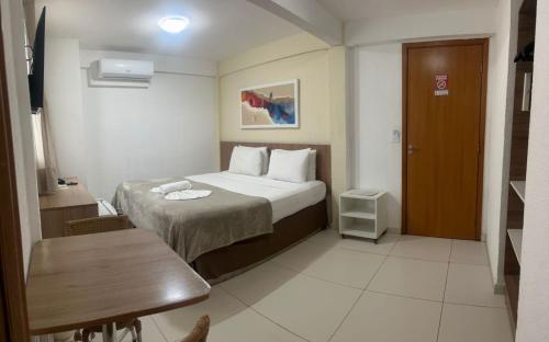 a bedroom with a bed and a table and a chair at Conde Hotel Maceió in Maceió