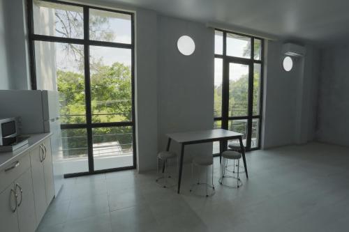 a kitchen with a table and chairs in a room with windows at Shekvetili Sunset Apartments in Shekhvetili