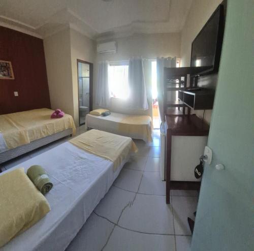 a hotel room with two beds and a television at Pousada Elshadai in Uruçuca