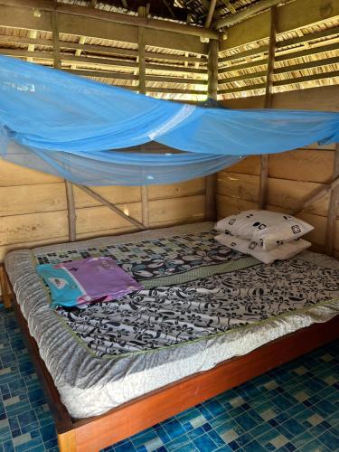 a bed in a room with a blue canopy at Mentawai Tribe Experience & Private Beach Camp in Pulau Masilo