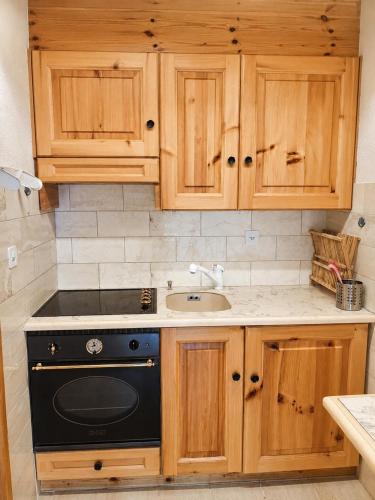 a kitchen with wooden cabinets and a black stove at Vue Alpes imprenable - Centre - 4 Vallées in Nendaz