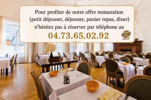 a dining room with tables and chairs and a sign at Hôtel du Parc in Le Mont-Dore