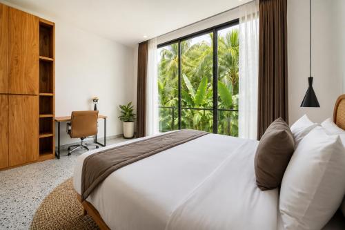 a bedroom with a white bed and a large window at Village Berawa in Badung