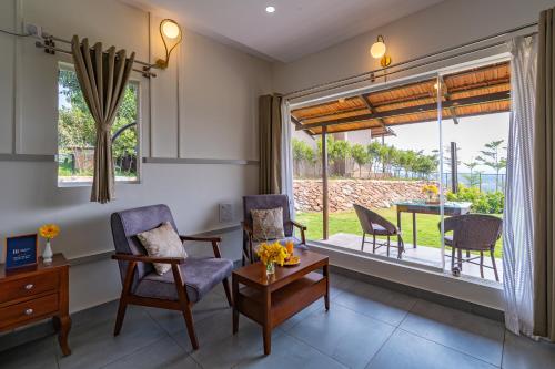 a living room with chairs and a table and a window at Ravishing Retreat Resort in Rāmanagaram