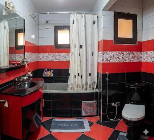 a red and white bathroom with a toilet and a sink at appartement chaleureux in Oran