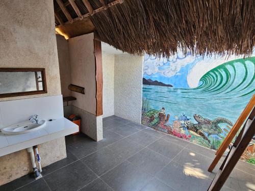 a bathroom with a sink and a painting on the wall at Belar Reef Bungalows in Nembrala