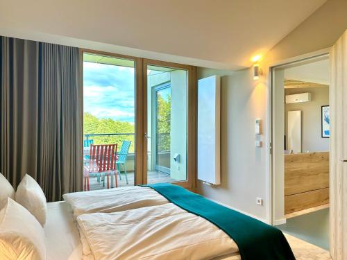 a bedroom with a bed and a balcony at SEEZIEGE Uckermark - Ferienwohnungen am Carwitzer See in Thomsdorf