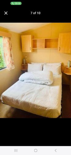 a bedroom with a bed with white sheets and pillows at Caravan 63 Fishguard Holiday Park in Fishguard