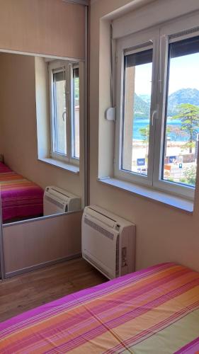 a bedroom with a mirror and a bed and a window at Downtown Apartment in Kotor