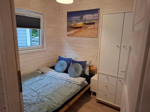 a small bedroom with a bed with blue pillows at Domek nad morzem 79 in Stegna