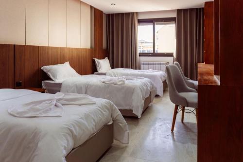 a hotel room with two beds and a chair at Hostel Tamim in Fort de lʼEau