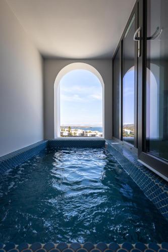 a swimming pool in a hotel with two windows at Niabelon Suites - Private Jacuzzi Sunset View in Oia