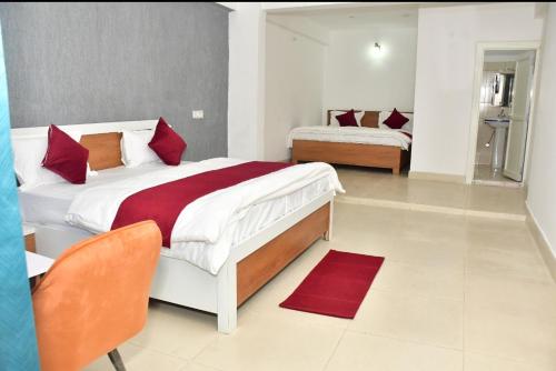 a bedroom with two beds with red pillows at Vybent hotel kainchi dham in Bhowāli
