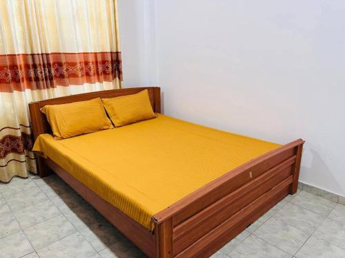a bedroom with a bed with a yellow bedspread at Kamaleswari Villa Trincomalee in Trincomalee
