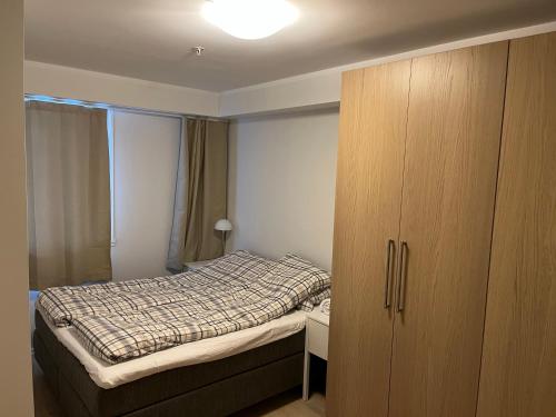 a small bedroom with a bed and a wooden cabinet at Geilo Superior leilighet in Geilo