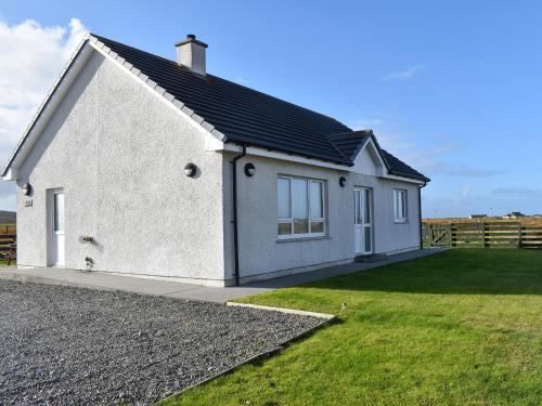a white house with a black roof at Lochboisdale Cottage in Lochboisdale