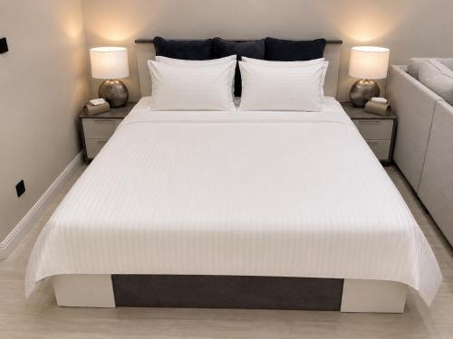 a large white bed in a room with two lamps at Sukoon Al Jubail in Al Fanātīr