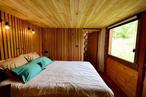 a bed in a wooden room with a window at Les Yourtes de La Valette in Floreffe