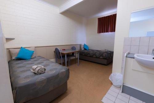 a small room with a bed and a sink at The Argent Motel in Broken Hill