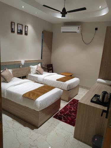 a bedroom with two beds and a ceiling fan at Yash Residency in Bharāwās