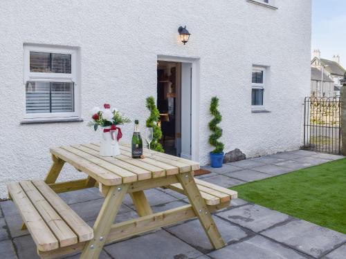 a picnic table with a bottle of wine and flowers at White Horses - Uk42776 in Newborough
