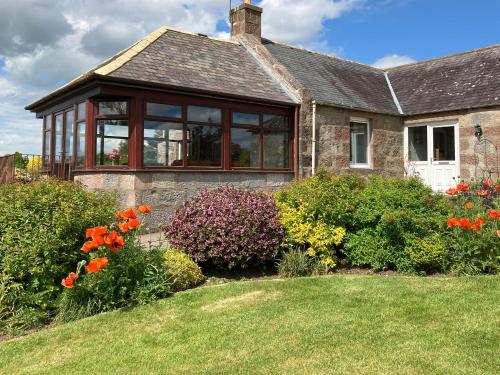 a house with windows and flowers in the yard at Sauchenshaw Cottage in Maryculter