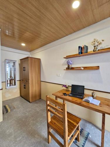 a room with a wooden desk with a laptop on it at Kotheybari homestay in Pakhyong