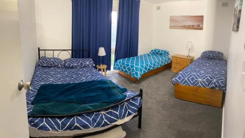 a bedroom with two beds with blue and white comforters at Goolwa Retreat in Goolwa North