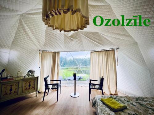 a bedroom with a tent with a bed and chairs at Ozols in Vecpiebalga
