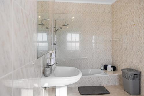 a white bathroom with a tub and a sink at Casa MiRaMar in Mosteiros
