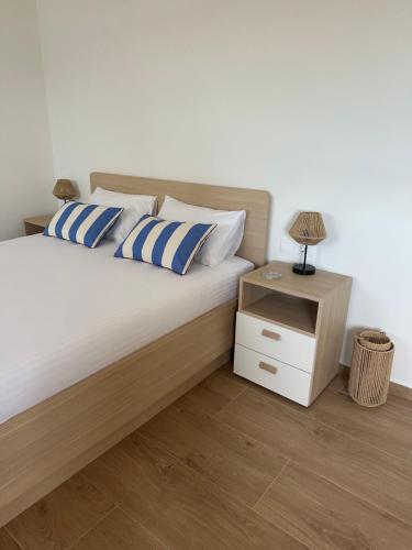 a bed with blue and white pillows and a night stand at Apartments Seafront in Pupnat