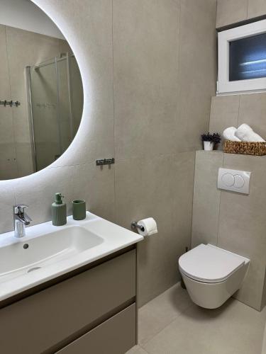 a bathroom with a sink and a toilet and a mirror at Apartments Seafront in Pupnat