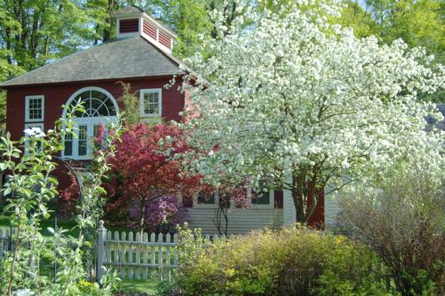 a red house with a white fence and a flowering tree at Arlington Inn & Spa in Arlington