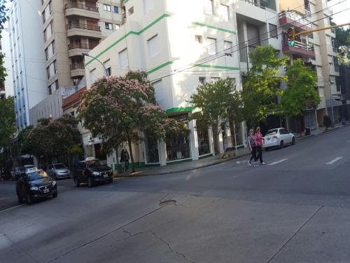 two people crossing a street in a city with buildings at Hotel Urca in Mar del Plata