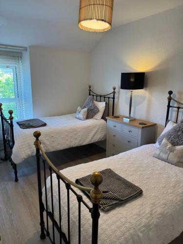 a bedroom with two beds and a table and a lamp at The Hideaway in Llandudno