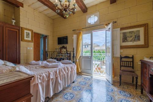 a bedroom with a bed and a sliding glass door at Ta' Kullarina Farmhouse in Żebbuġ