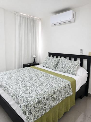 a bedroom with a bed with a green and white comforter at Hostal Santa Barbara in Santo Domingo