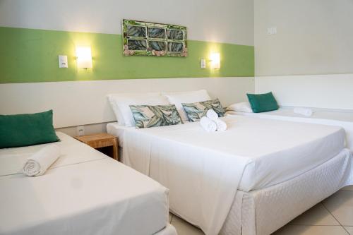 two beds in a room with green and white at Pousada Mar E Mata in Guarapari