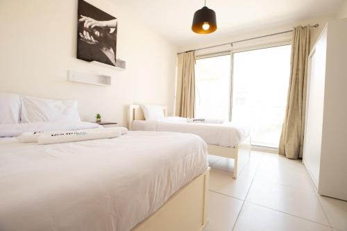 two beds in a white room with a window at Marina Marassi in El Alamein