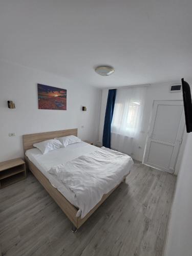 a bedroom with a white bed and a door at Casa Ana Maria in Vama Veche