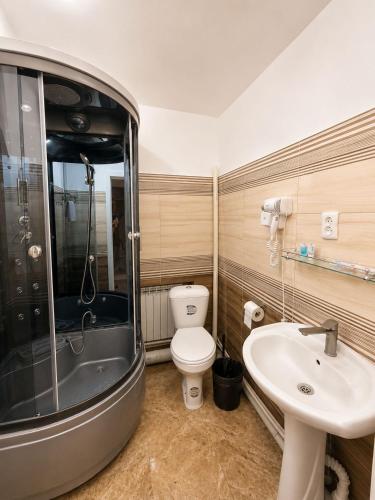 a bathroom with a toilet and a sink and a shower at Grand Sky Hotel in Almaty