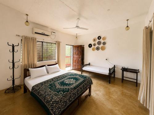 a bedroom with a bed and a bench in it at Bhumika by evaddo stays in Mandrem