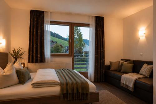 a bedroom with a bed and a window with a couch at Appartments Gerlos Am Bach - Riverside in Gerlos