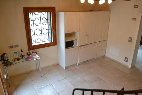 a kitchen with white cabinets and a window and a table at Casale La Rocchetta in Lonigo