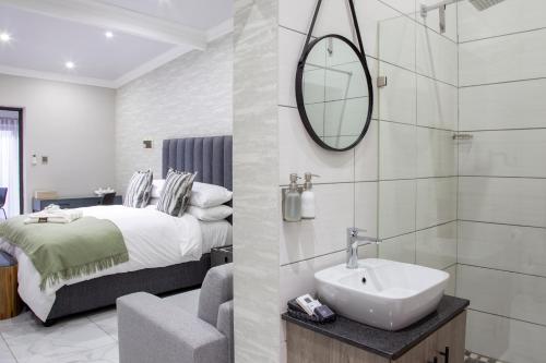 a bathroom with a bed and a sink and a mirror at Guest at 58 in Lydenburg