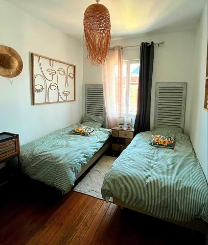 two twin beds in a room with a window at La Villa Turquoise in Le Tréport